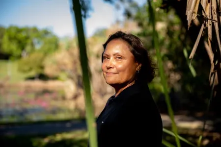 Picture of a woman looking towards camera with natural flora in the back